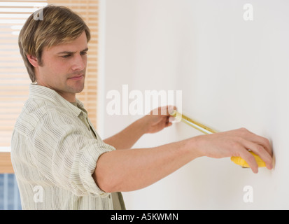 Mann, die Wand mit Maßband messen Stockfoto