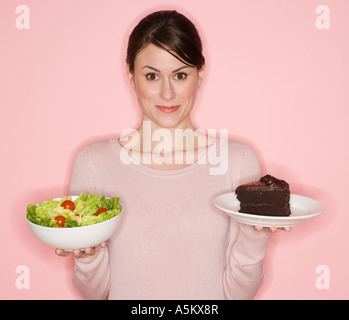 Frau Holding Salat und Kuchen Stockfoto