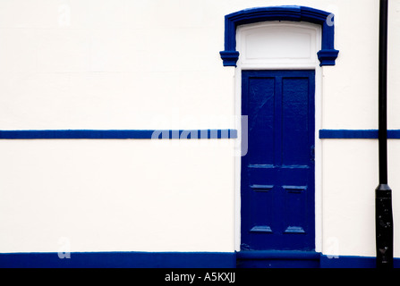 Blaue Tür, weiße Wand, schwarz Laternenpfahl. Stockfoto