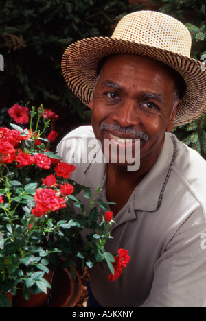 Afrikanische amerikanische Mann mit Blumen im Garten Stockfoto
