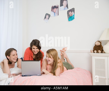 Mädchen im Teenageralter Blick auf Laptop auf Bett Stockfoto