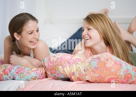 Mädchen im Teenageralter lachend auf Bett Stockfoto