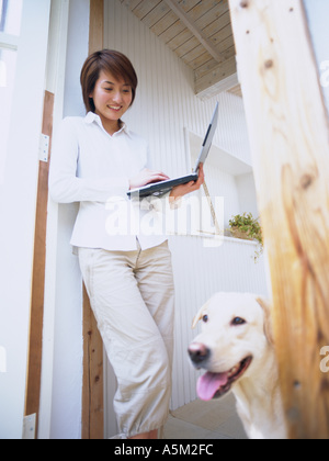 Asiatische Frau lächelnd an ihrem Hund Stockfoto