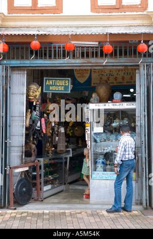 Mann sucht im Fenster ein Antiquitätengeschäft in Jonkers Street in Malacca Stockfoto