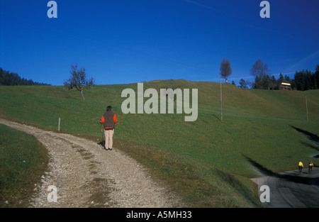 Frau auf Schotterstraße Blick hinunter auf die Straße mit Radfahrer vorbei an Schweizer Alpen der Schweiz wandern Stockfoto