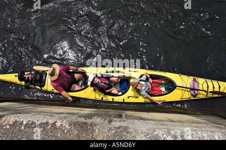 Nach oben: ein Vater und seine beiden Söhne an Bord eines gelben Kajak halten die stabilisierenden Linien wie die Sperre füllt um ihr Boot zu erhöhen Stockfoto