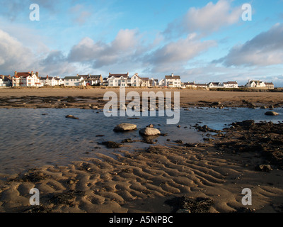 Sandstrand bei Ebbe Rückblick auf Strandpromenade Häuser im Dorf mit Sand Wellen im Vordergrund im Winter Rhosneigr Anglesey Stockfoto