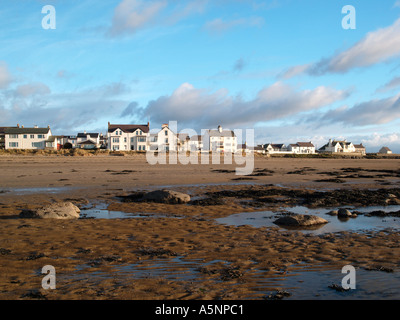 Sandstrand bei Ebbe Rückblick auf Strandpromenade Häuser im Dorf mit Sand Wellen im Vordergrund im Winter Rhosneigr Anglesey Stockfoto