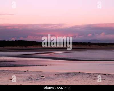 Sonnenuntergang über die Bucht von LLANDDWYN bei Ebbe im Winter von Llanddwyn Island Newborough Anglesey North Wales UK Stockfoto