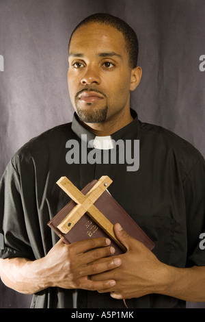 Mann des Gottes (Modell) hält ein Kreuz und Bibel. Stockfoto