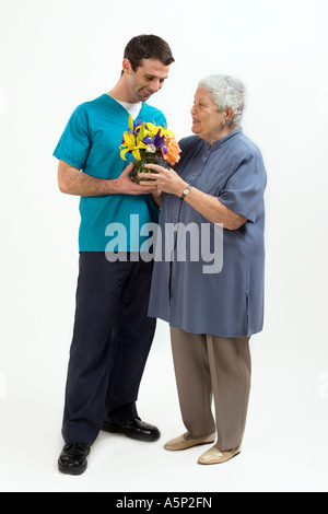 Patient gibt Blumen zu ihrem Betreuer.  OR Pflegeperson gibt Blumen für seine Patienten. Stockfoto