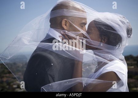 Profil von einem frisch verheirateten Paar küssen einander unter einem Schleier Stockfoto