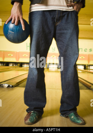 Niedrige Schnittansicht eines jungen Mannes hält eine Bowling-Kugel Stockfoto