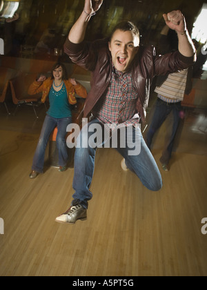 Junger Mann springt in Aufregung in einer Bowlingbahn Stockfoto