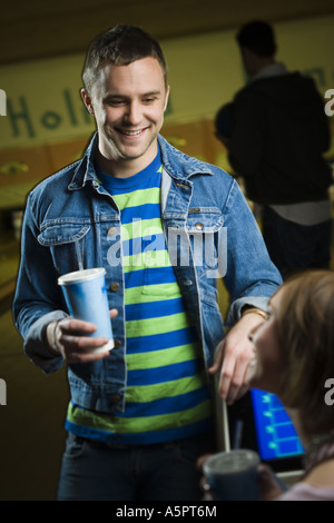 Junger Mann und ein junges Mädchen halten Gläser Cola und sahen einander Stockfoto