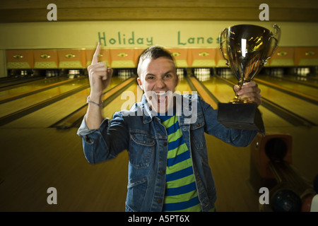 Porträt eines jungen Mannes hält eine Bowling Trophäe und Gestikulieren mit seiner hand Stockfoto