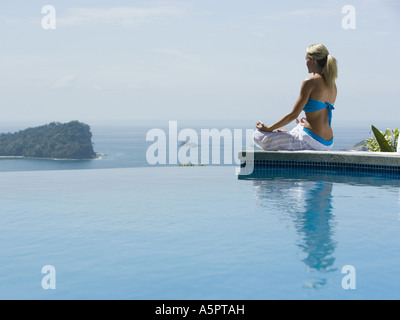 Rückansicht einer Mitte erwachsenen Frau sitzen in einem Lotus-Position am Pool Stockfoto