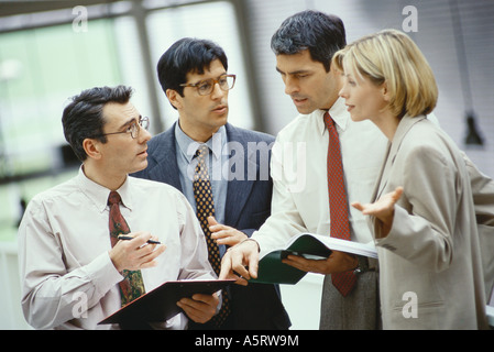 Vier Kollegen stehen Diskussion Dokument und agenda Stockfoto