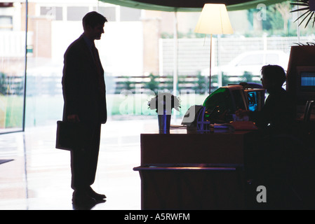 Geschäftsmann, stehende silhouette im Gespräch mit der Rezeption, Stockfoto