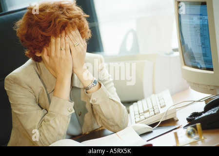 Geschäftsfrau sitzen am Schreibtisch, Kopf haltend Stockfoto