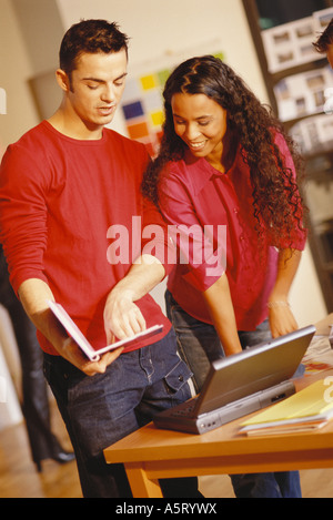 Junger Mann und Frau stehen neben Laptop-Mann zeigte auf Benutzer Handbuch Stockfoto