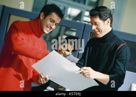 Drei Kollegen betrachten Dokument, Lächeln Stockfoto