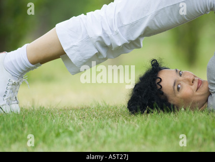 Junge Frau tut Pflug-Pose im Freien, lächelnd in die Kamera Stockfoto