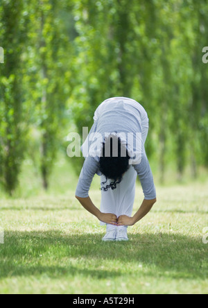 Junge Frau, die Dehnung auf Rasen Stockfoto