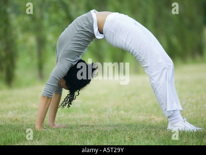 Junge Frau, die Brücke auf dem Rasen zu tun Stockfoto