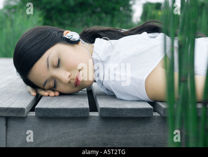 Frau liegt auf dem Deck, Kopfhörer anhören Stockfoto