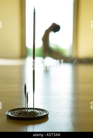 Yoga-Kurs, Frau tun Kobra-Pose, Fokus auf Weihrauch im Vordergrund Stockfoto