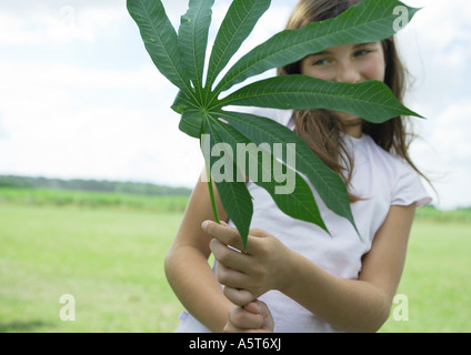 Mädchen stehen halten Cassava Blatt Stockfoto