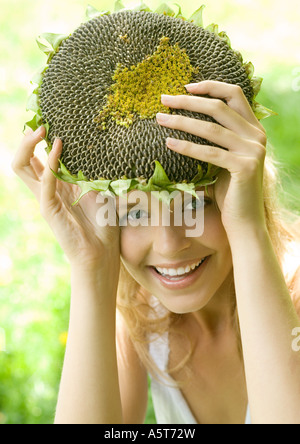 Junge Frau, die getrockneten Sonnenblumen über Kopf hochhalten Stockfoto