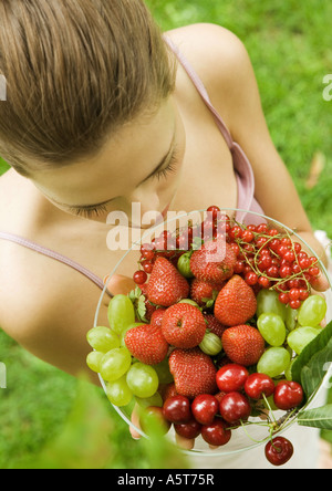 Young woman holding up bowl of fruit Stockfoto