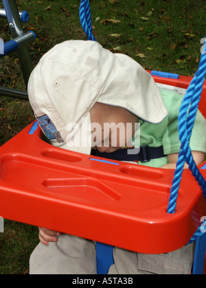 Kleiner Junge schlafend in einer roten Gartenschaukel einen grauen Sonne Hut Stockfoto