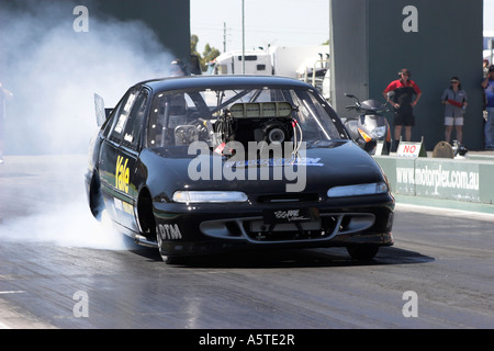 Australischen Holden Commodore Supercharged Outlaws ziehen Auto rauchigen Burnout auf Viertel Meile Rennstrecke durchführen Stockfoto