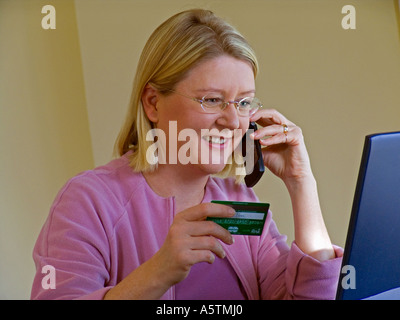 Frau am Telefon benutzt gerne ihre Kreditkarte, um online mit ihrem Laptop-Computer-shop Stockfoto