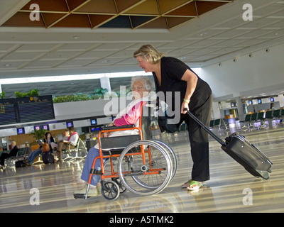 Ältere Frau im Rollstuhl mit Begleiter Betreuer am Flughafen Halle Reisen vorbereiten Stockfoto