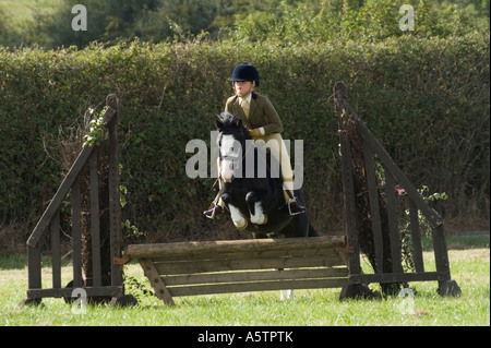 Junges Mädchen auf Pony springen Zaun im Springreiter Wettbewerb auf Land, UK Stockfoto