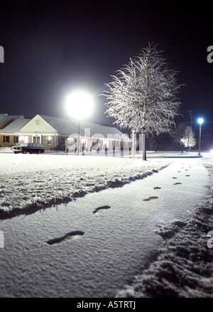 Fussspuren im Schnee Bürgersteig Weg in der Nacht mit Lampe Licht und vereisten Baum, Apartment-Komplex, Philadelphia Pennsylvania USA Stockfoto