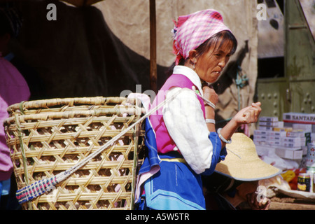 Naxi-Frau in traditioneller Kleidung, großen Weidenkorb auf dem Rücken, Wase-Markt in der Nähe von Dali, Yunnan Provinz, China. Stockfoto