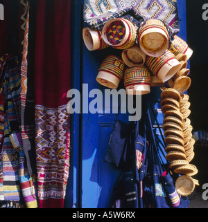 Traditionelle Körbe zum Verkauf hängen in der Sonne am blauen Ladentür, Luang Prabang, Laos. Stockfoto