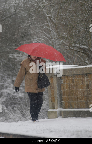 Dame zu Fuß entlang dem Schnee bedeckt Pflaster an einem Winter-Morgen in England. Stockfoto