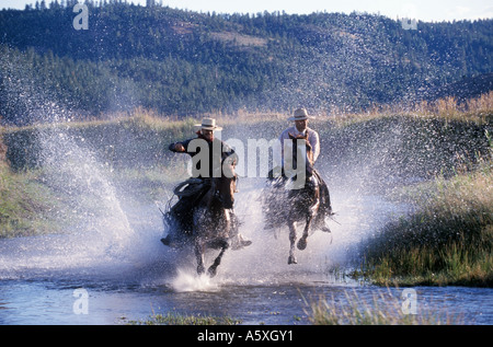 Zwei Cowboys reiten durch einen Fluss Oregon USA Stockfoto