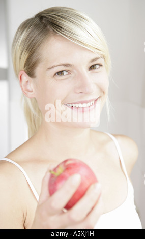 Junge Frau hält Apfel lächelnd Porträt hautnah Stockfoto