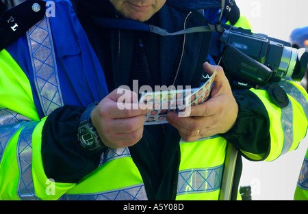 Metropolitanpolizei Spotter mit Blick auf seine Fahndungsfotos bekannten Fußball Trouble Maker Wales UK Videokamera Stockfoto