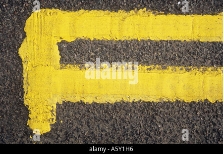 Detail aus direkt oberhalb der neu lackiert doppelte gelbe Linien mit Ende Bar auf schwarzem Asphalt Fahrbahn Stockfoto