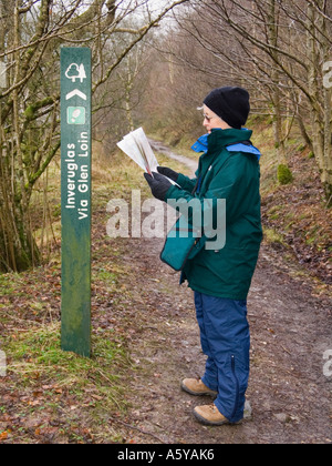 Wanderweg Zeichen zu Inveruglas durch "Lion Glen" mit älteren weiblichen Walker. Arrochar Argyll Bute Schottland, Vereinigtes Königreich Stockfoto