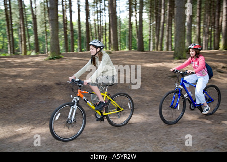 Zwei Mädchen im Teenageralter Radfahren in Delamere Wald Cheshire Stockfoto