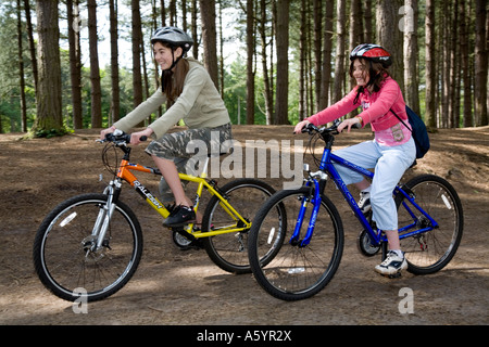 Zwei Mädchen im Teenageralter Radfahren in Delamere Wald Cheshire Stockfoto